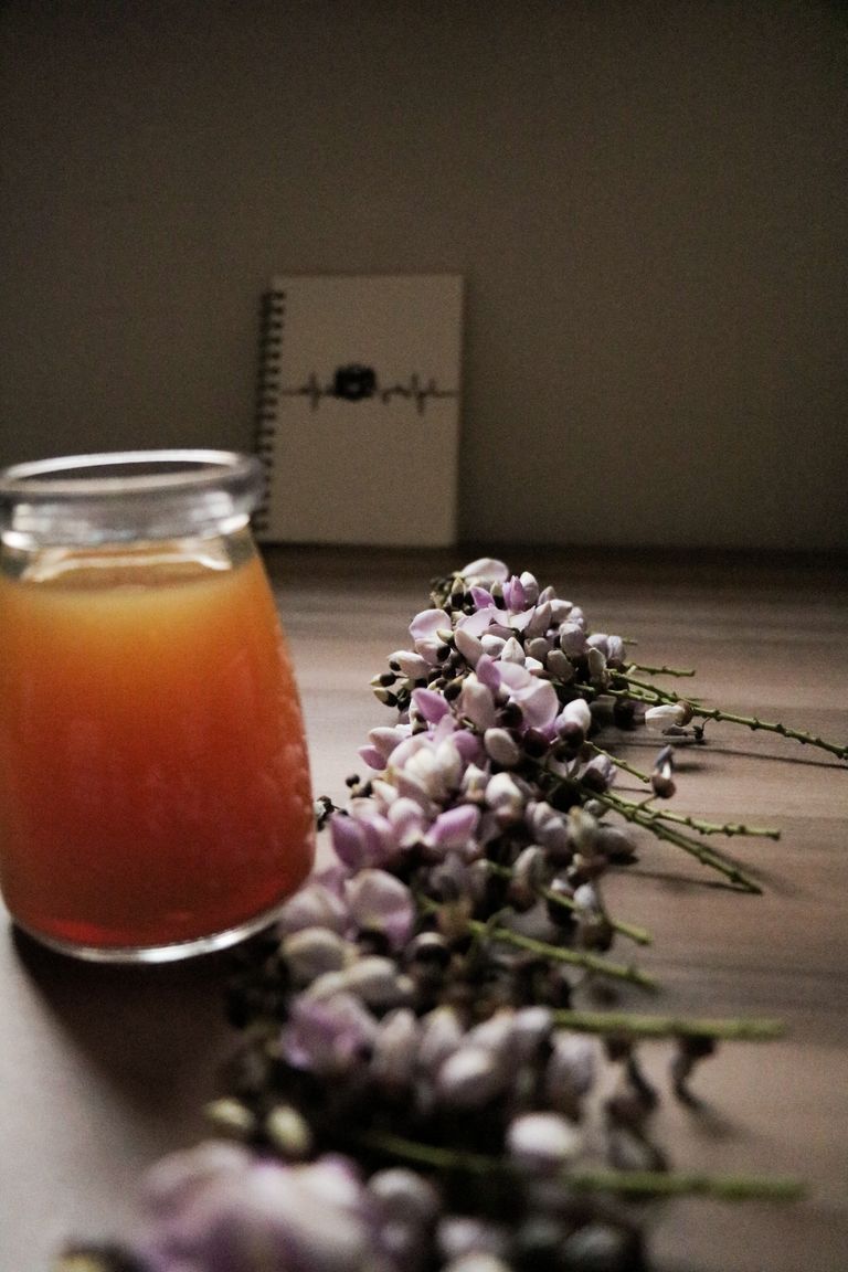 A close-up of a honey jar with purple flowers on a wooden table, perfect for natural and organic themes.