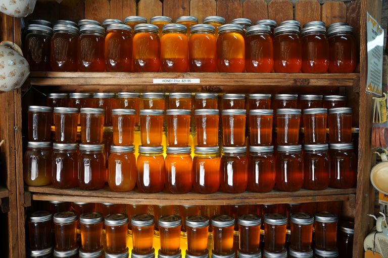 Assorted honey jars displayed on wooden shelves with varied colors and hues.